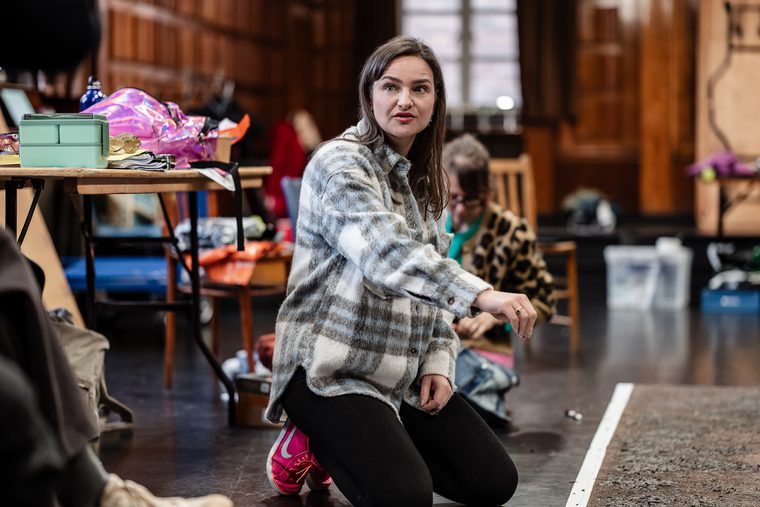 A wom an kneels on the floor pointing in a rehearsal room