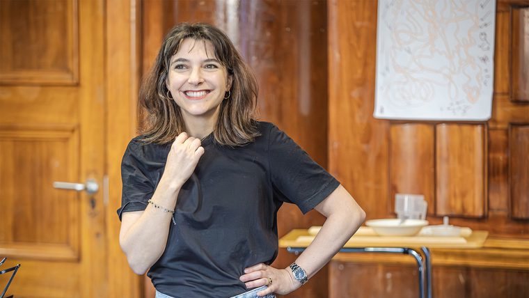 A woman in a black t shirt stands smiling