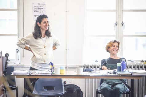 Two women smile behind a table