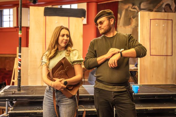 A man and woman look frustratingly at each other in the rehearsal room