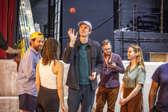 A man throws an apple in the air in the rehearsal room