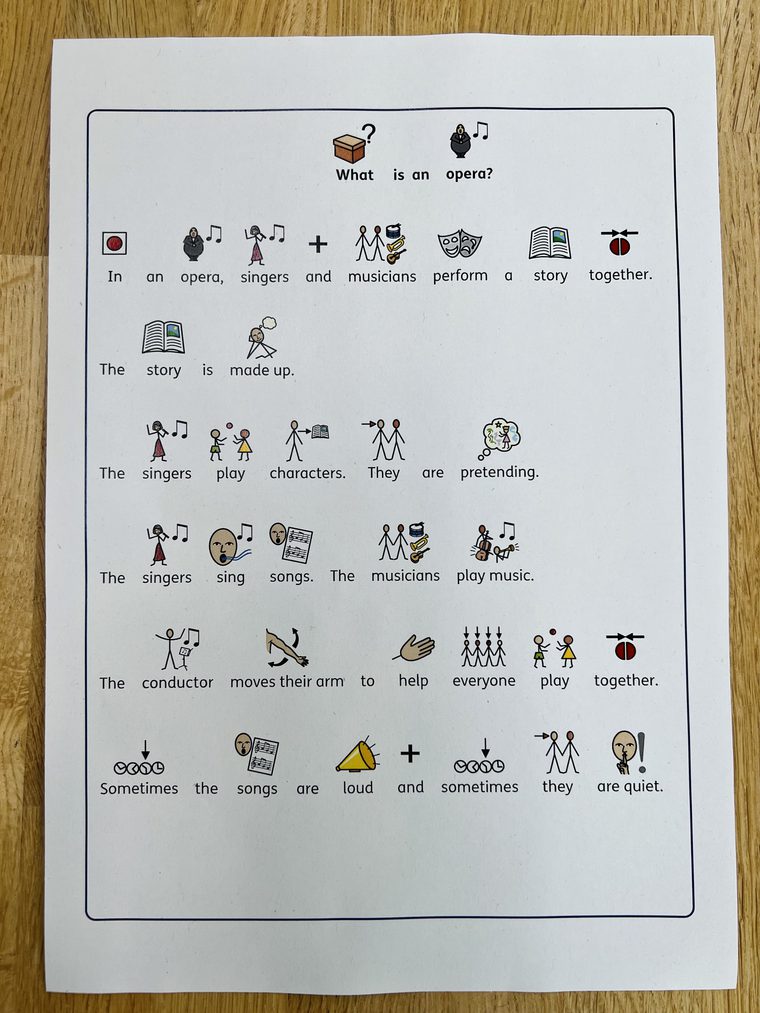 One sheet of white paper sits on a wooden table. A social story explaining an opera is printed on the page.