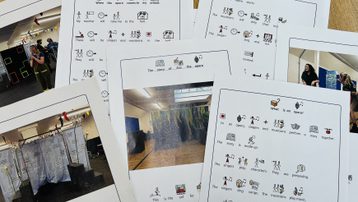 Seven sheets of white paper are scattered across a wood table. Social stories and pictures of opera sets are printed on the papers.