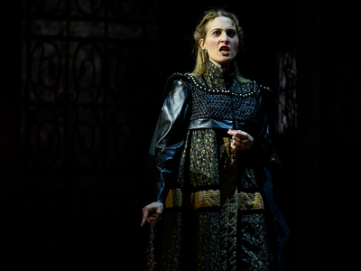Lucrezia Borgia stands wearing battle clothing centre stage. She is singing angrily.