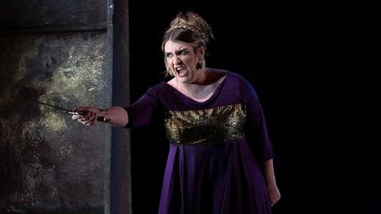 A woman in a purple dress points a dagger in anger