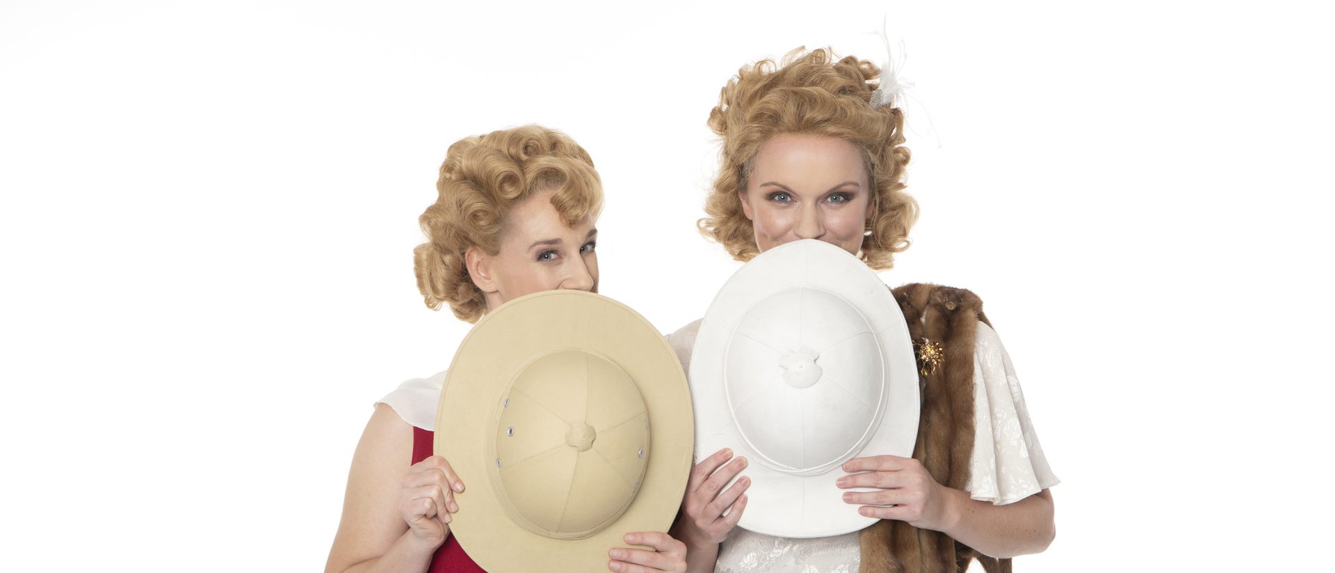 Season artwork for ETO's Così fan tutte, two sisters dressed in 1920's clothes, they are holding two hat's that explorers might wear, they are using them to hide their faces and are playfully peeking over the tops of the hats.