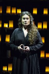 Belinda stands in a black dress with lanterns surrounding her