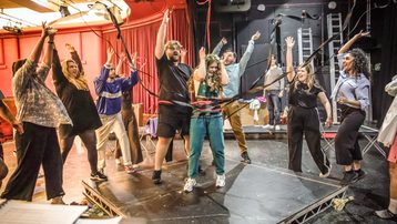 The Snowmaiden ensemble throws ribbons in the air around a woman wearing a flower crown.