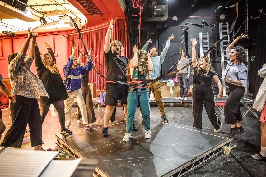 The Snowmaiden ensemble throws ribbons in the air around a woman wearing a flower crown.