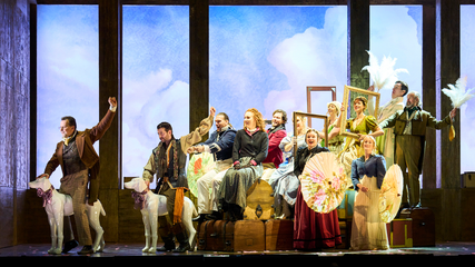 The cast of Il Viaggio a Reims form the image of a carriage and horses, using everyday items found within a hotel.